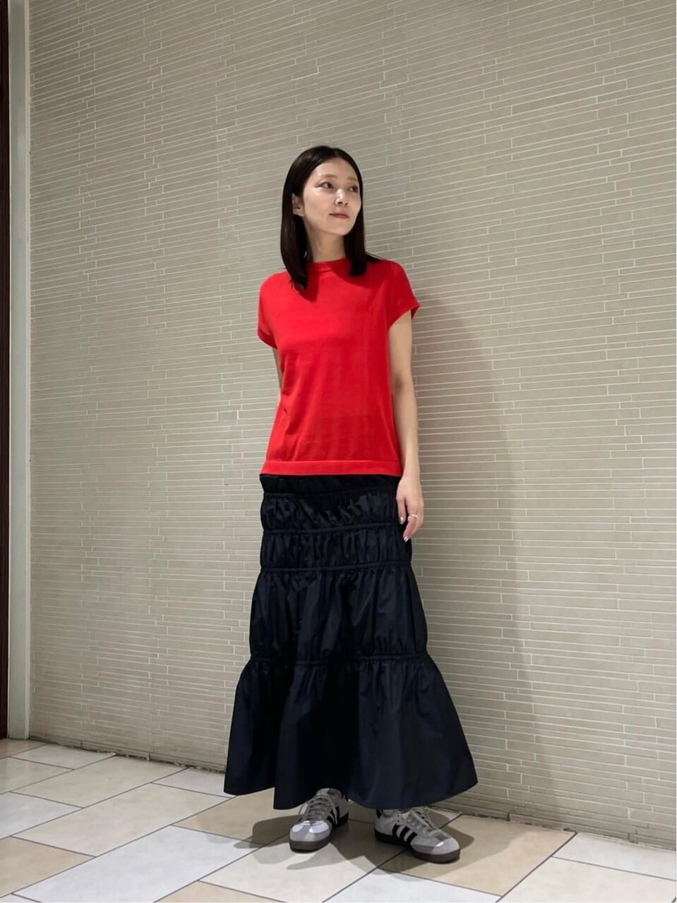 ベージュのトップス×黒スカートのコーデ