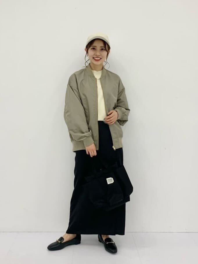 ブルゾンと黒スカートを着用した女性