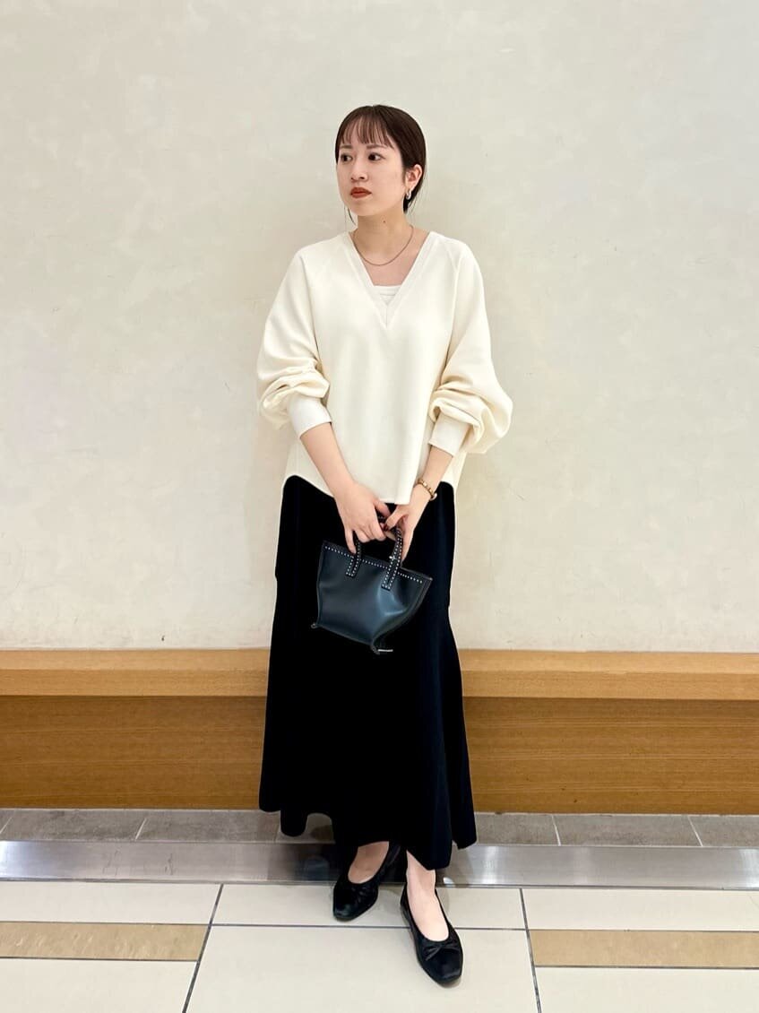 白ニットと黒スカートを着用した女性
