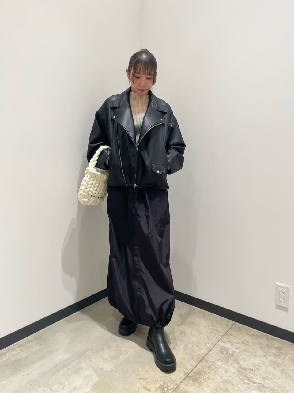 ライダースジャケットと黒スカートを着用した女性