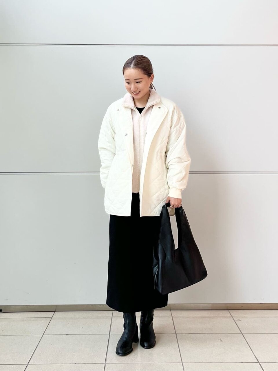 ブルゾンと黒スカートを着用した女性