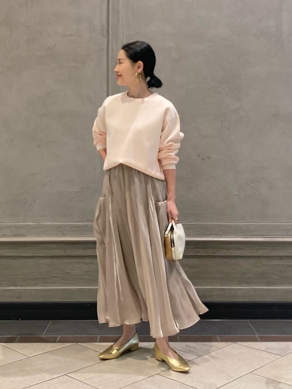 ピンクのニットとプリーツスカートを着た女性