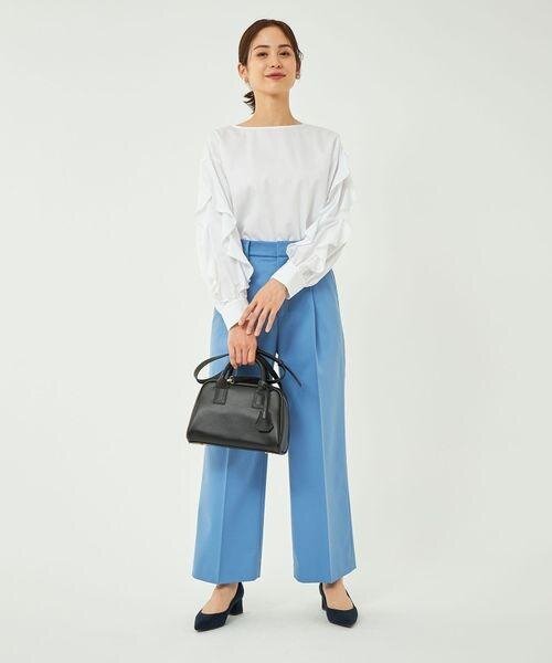 ホワイトのトップスにパステルブルーのワイドパンツを着用した女性