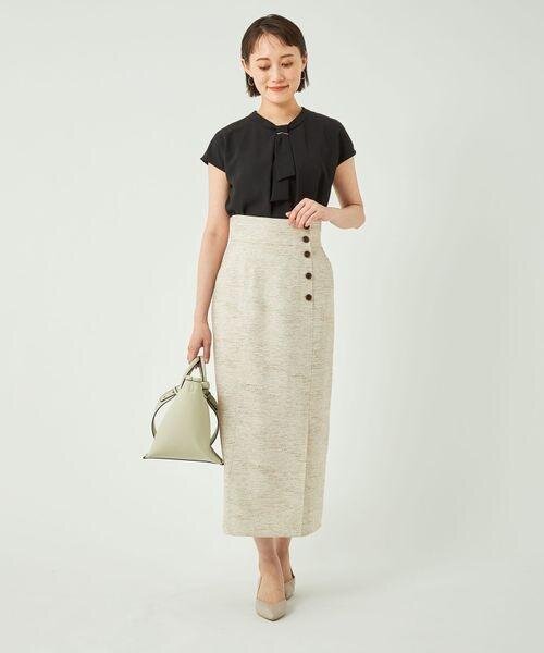 黒のトップスにタイトスカートを着用した女性