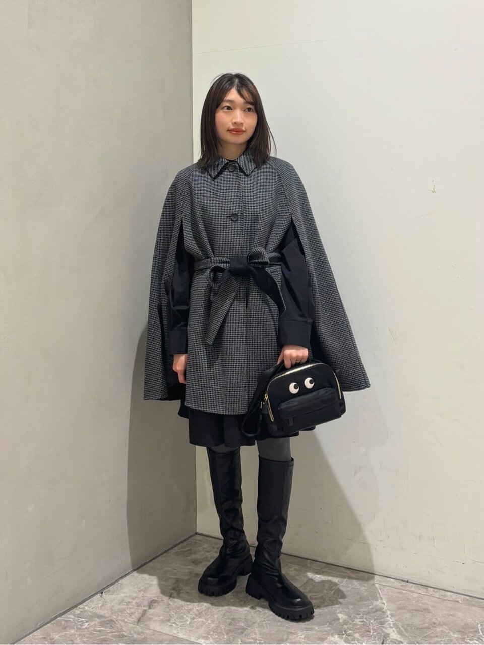 ケープコートとロングブーツを着た女性