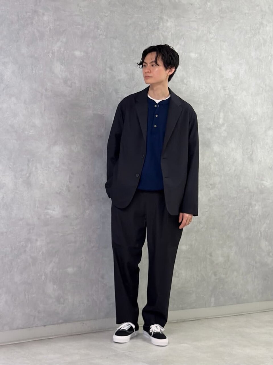 セットアップジャケットとヘンリーネックニットを着た男性