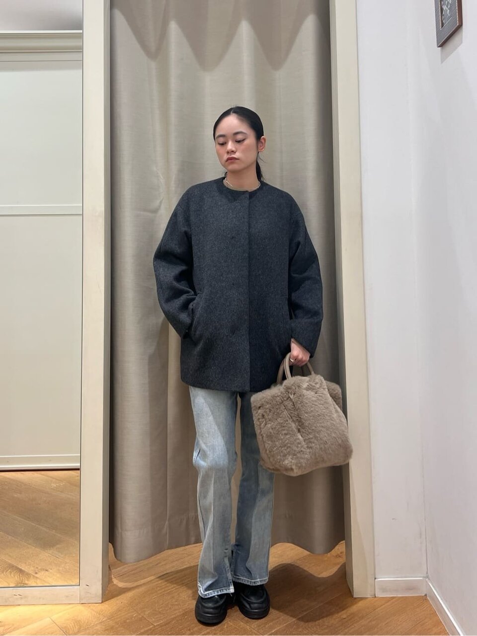 ノーカラーコートとハイウエストデニムを着た女性