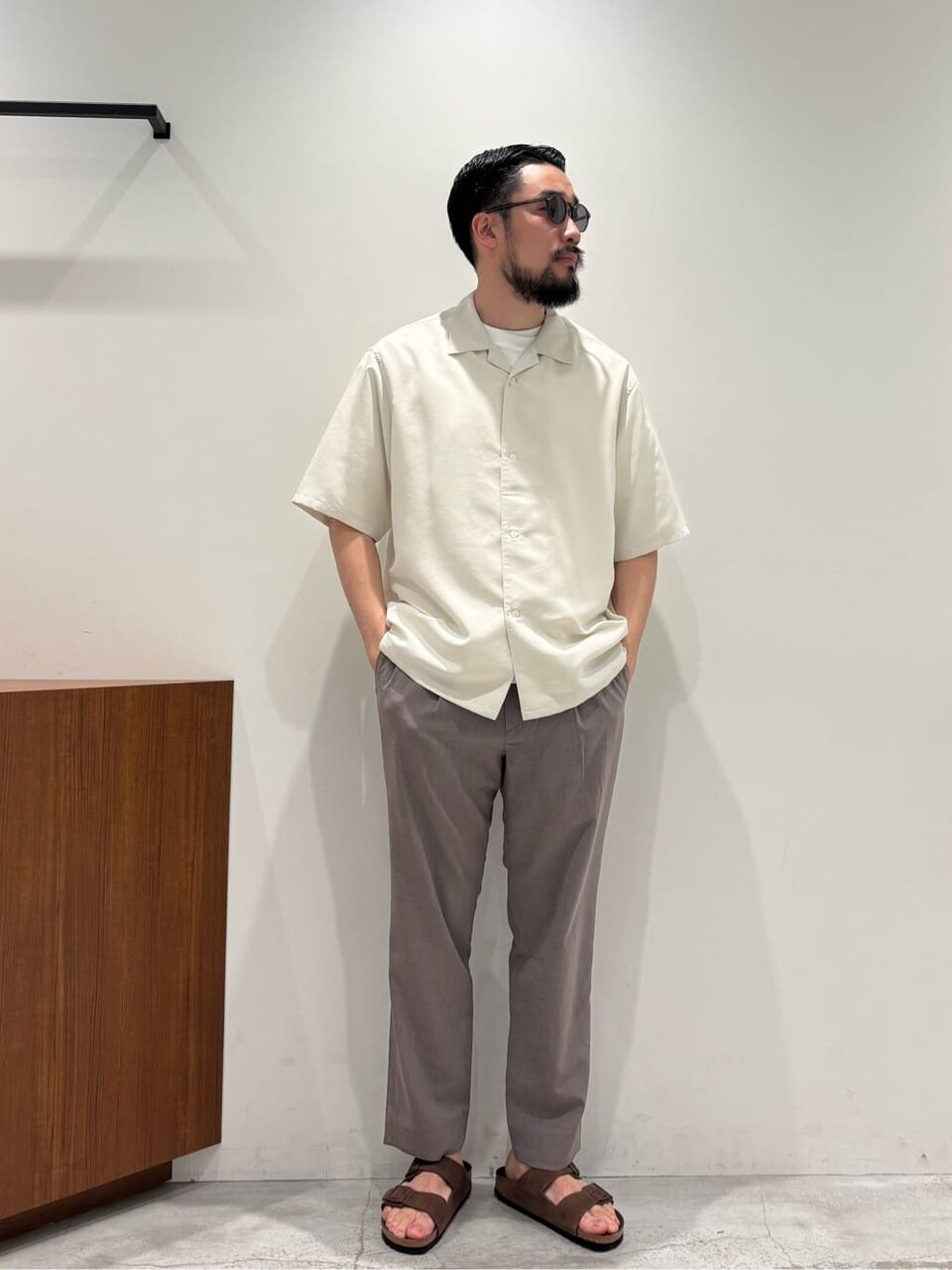 白のオープンカラーシャツとイージーパンツを着た男性