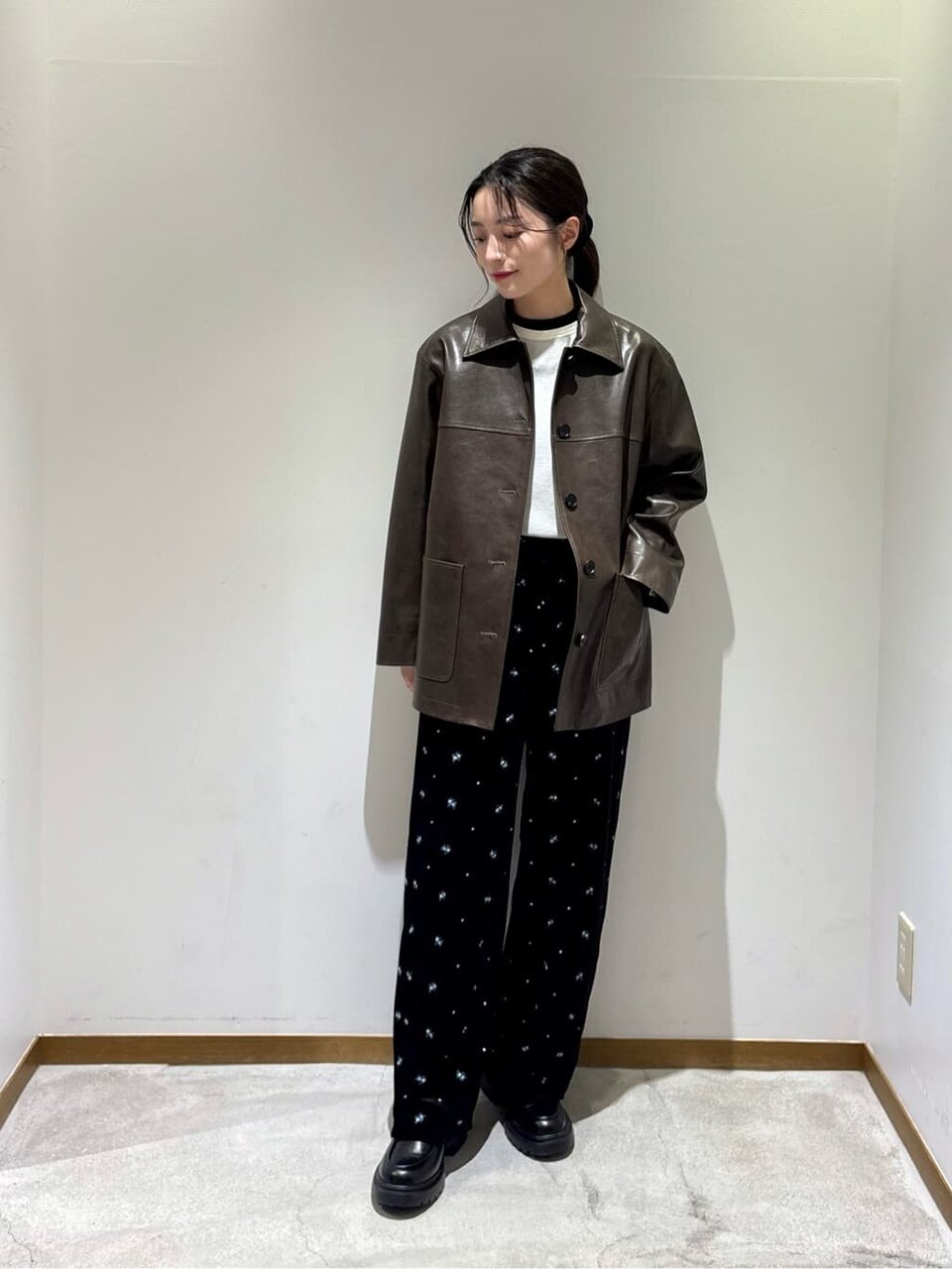レザーカバーオールとベロアパンツを着た女性