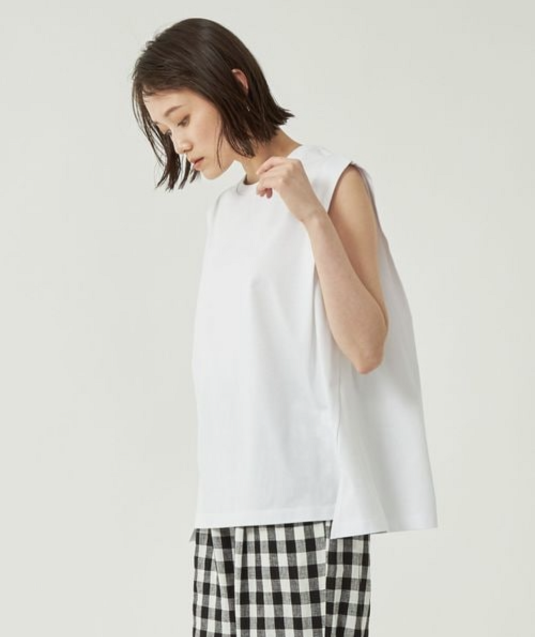 ホワイトのノースリブプルオーバーカットソーを着ている女性