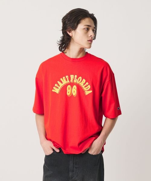 赤のロゴTシャツを着た男性の後ろ姿