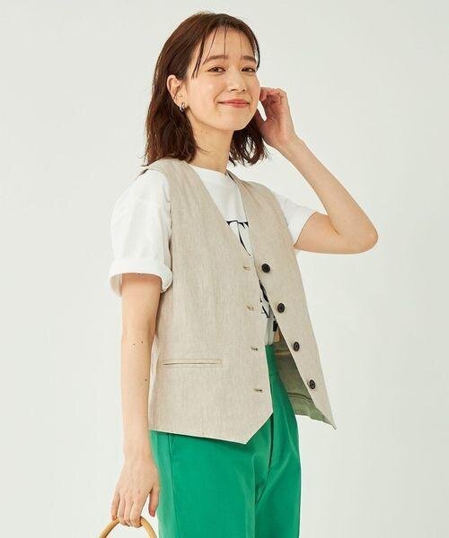ベージュのベストと緑のパンツの女性