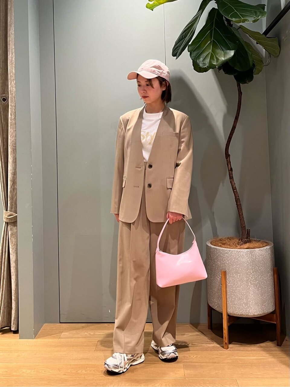 ジャケットのセットアップとキャップを身につけた女性