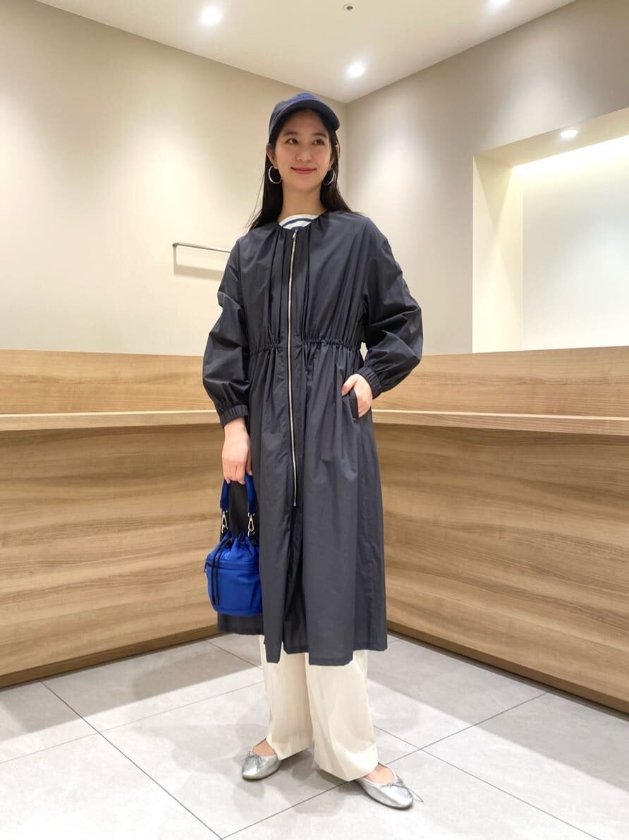 ノーカラーコートとキャップを身につけた女性