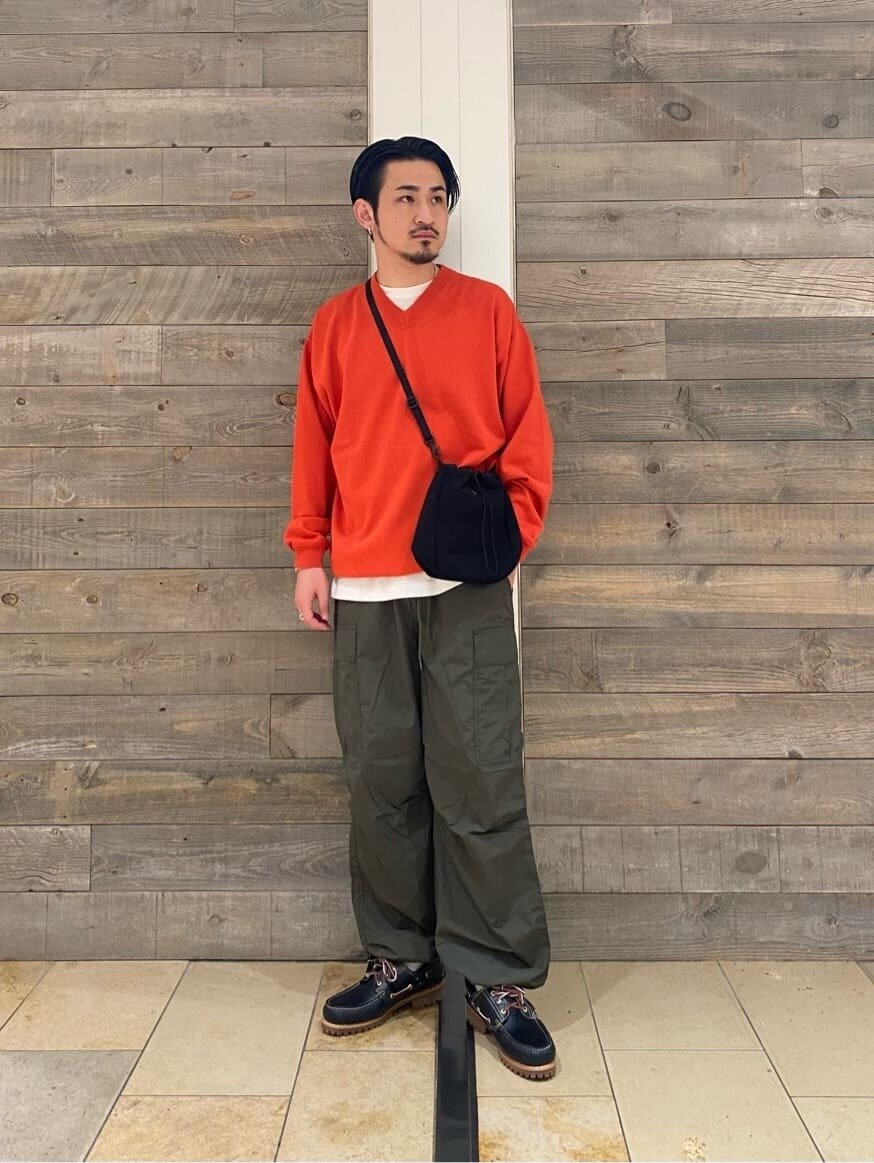 緑のカーゴパンツ×オレンジのVネックニットのコーデ