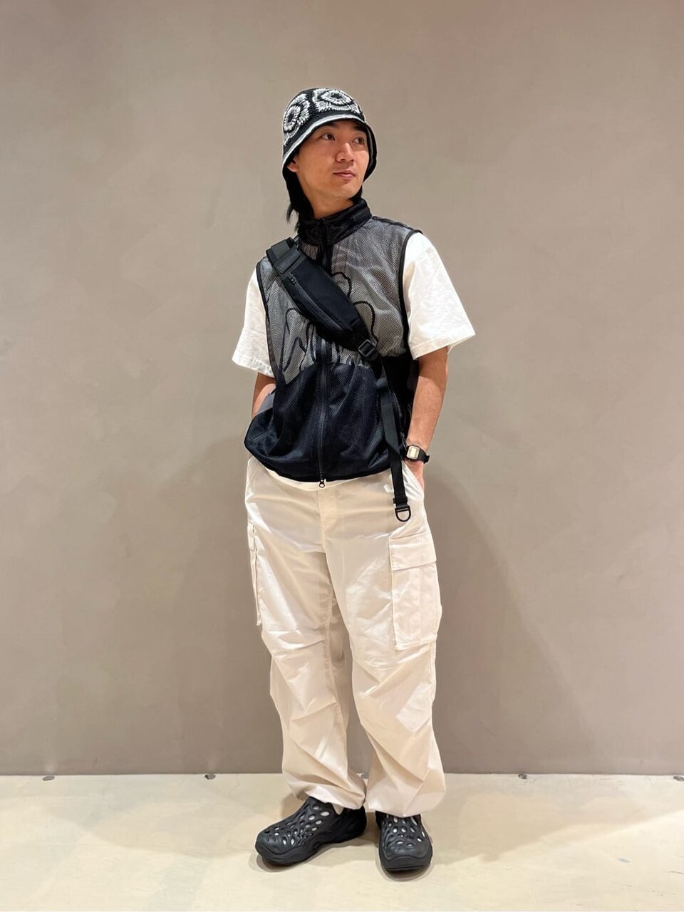 メッシュベストと白いカーゴパンツを着た男性