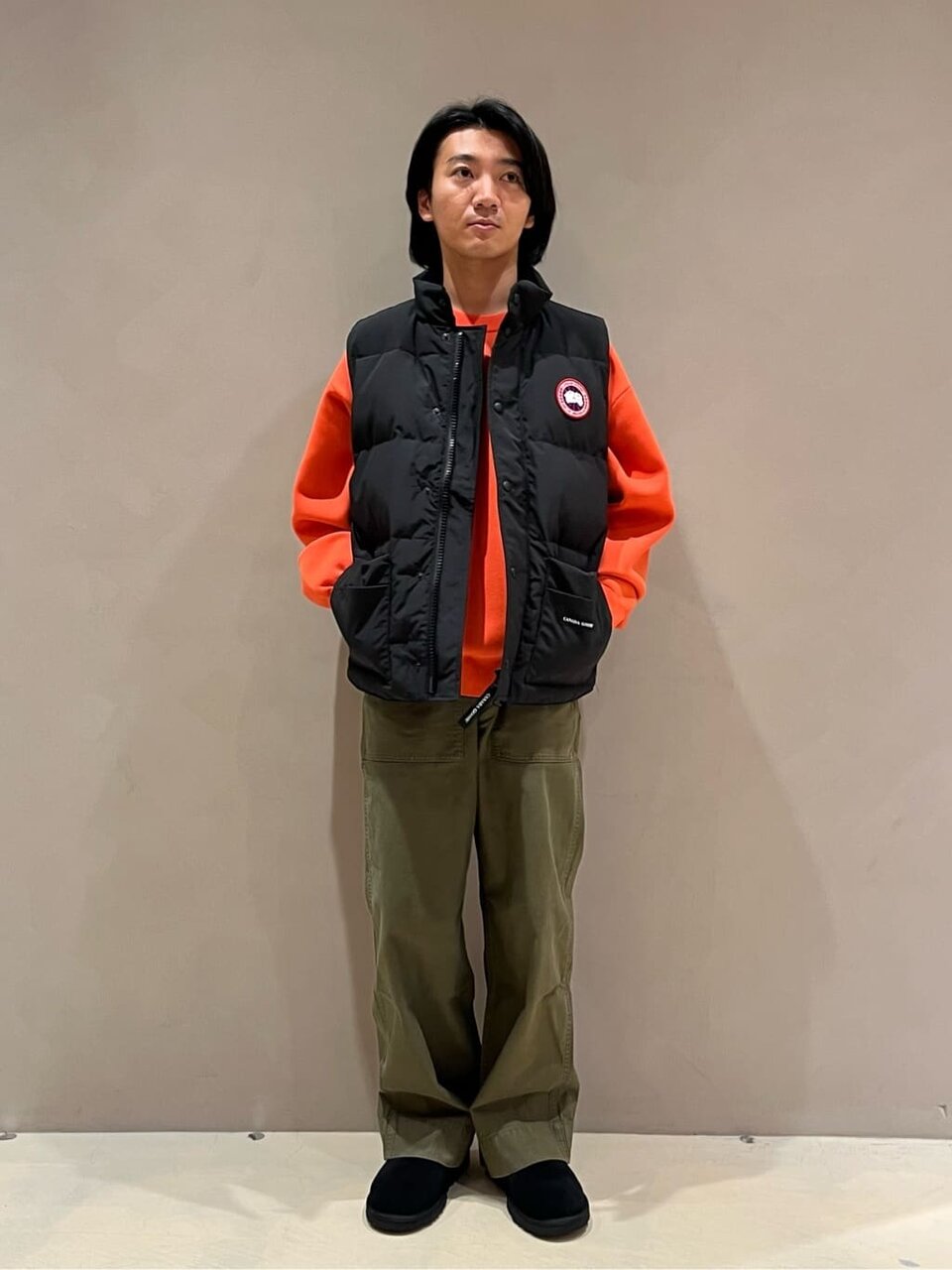 ダウンベストとオレンジのニットを着た男性
