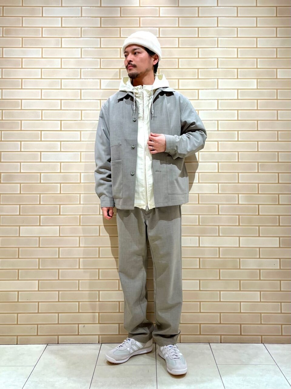 グレーのジャケットに白いニットキャップ姿の男性