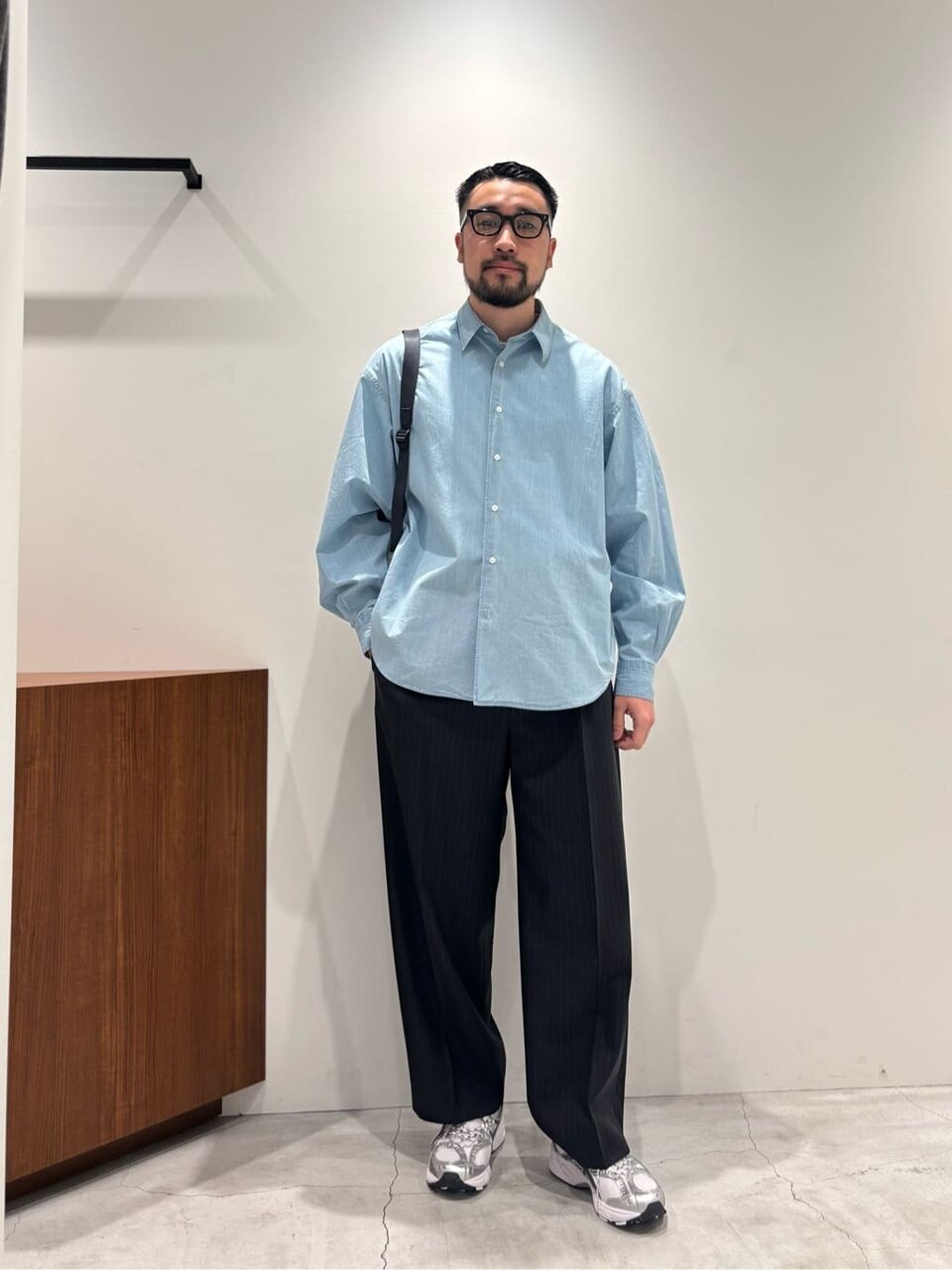 シャンブレーシャツに黒いパンツを着た男性