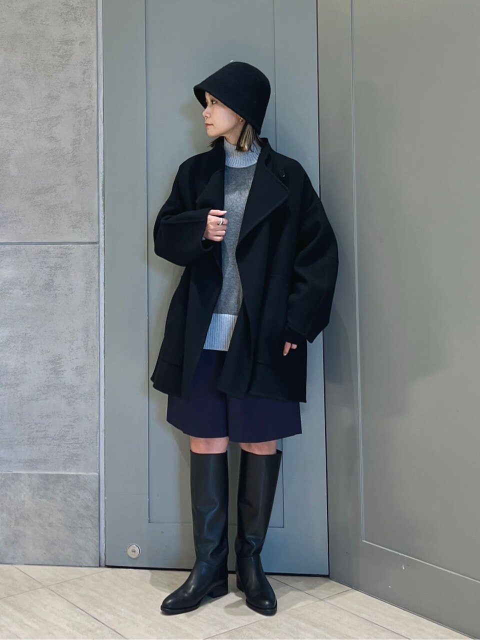 ノーカラーコートを着て帽子を被った女性