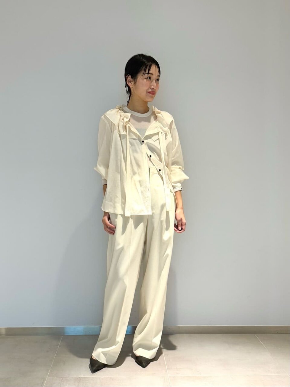 白いギャザーブラウスとパンツを着た女性