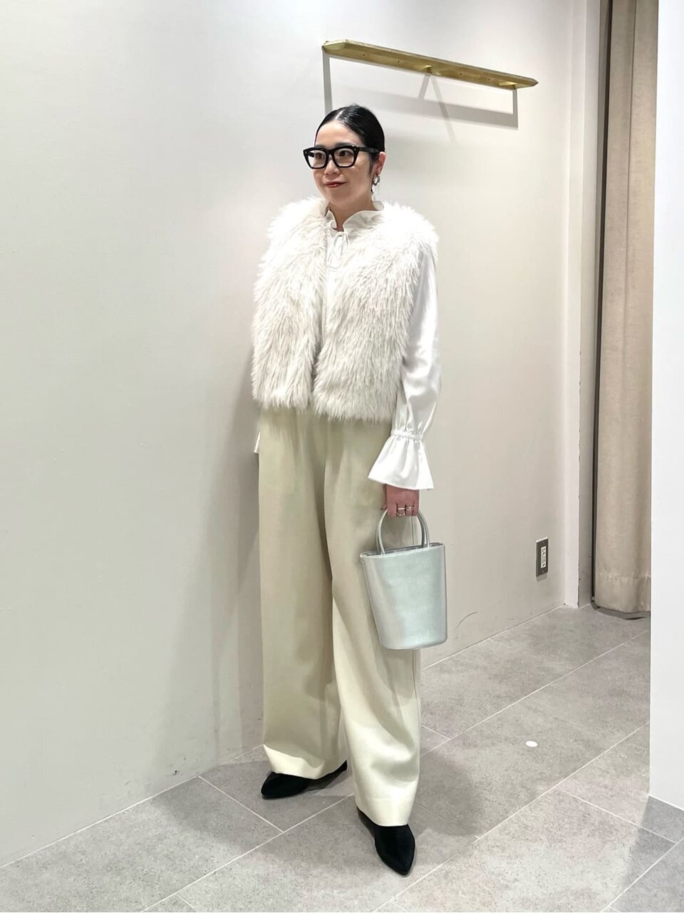 白いファーベストとパンツを着た女性