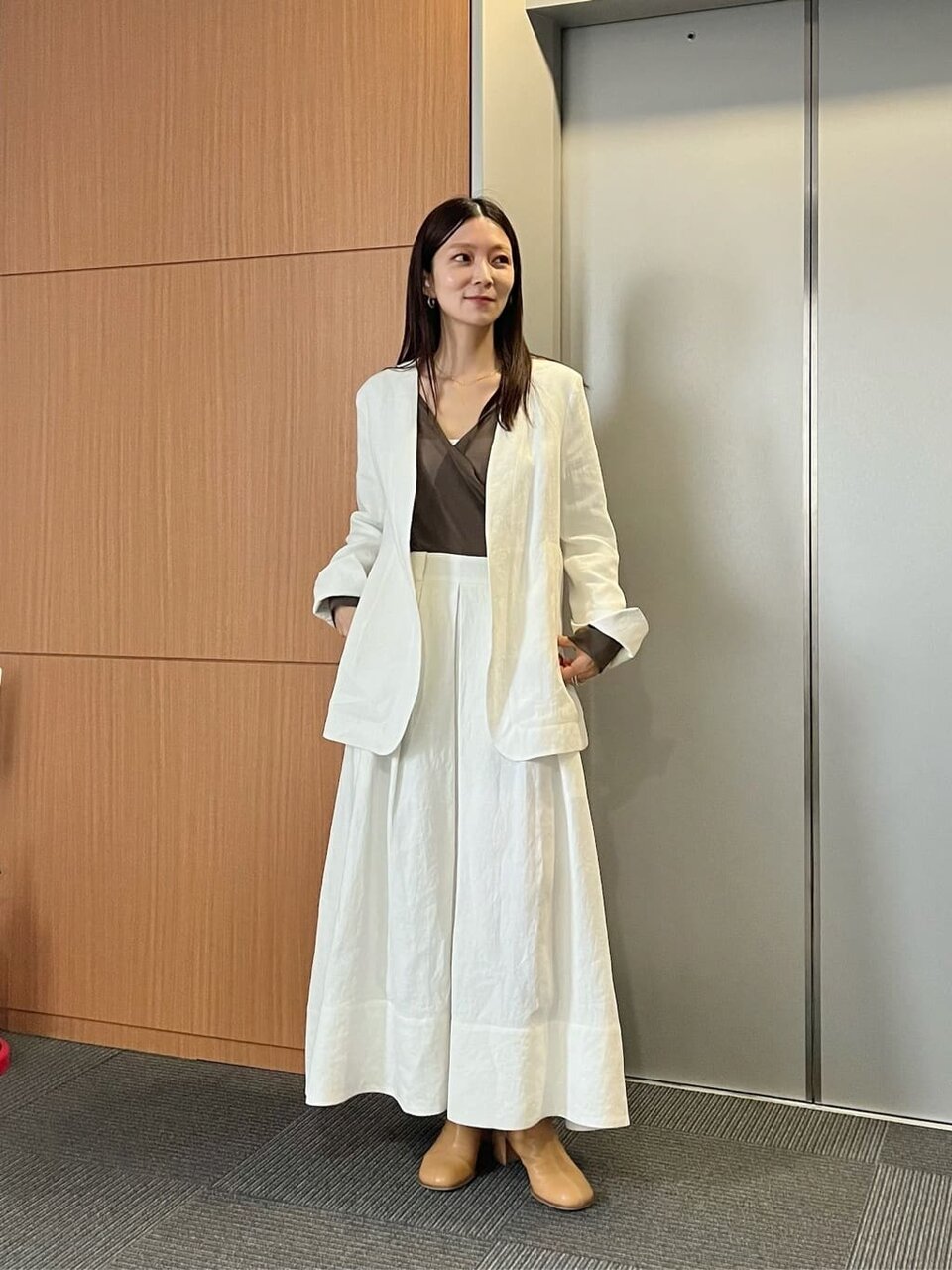 白いノーカラージャケットとスカートを着た女性