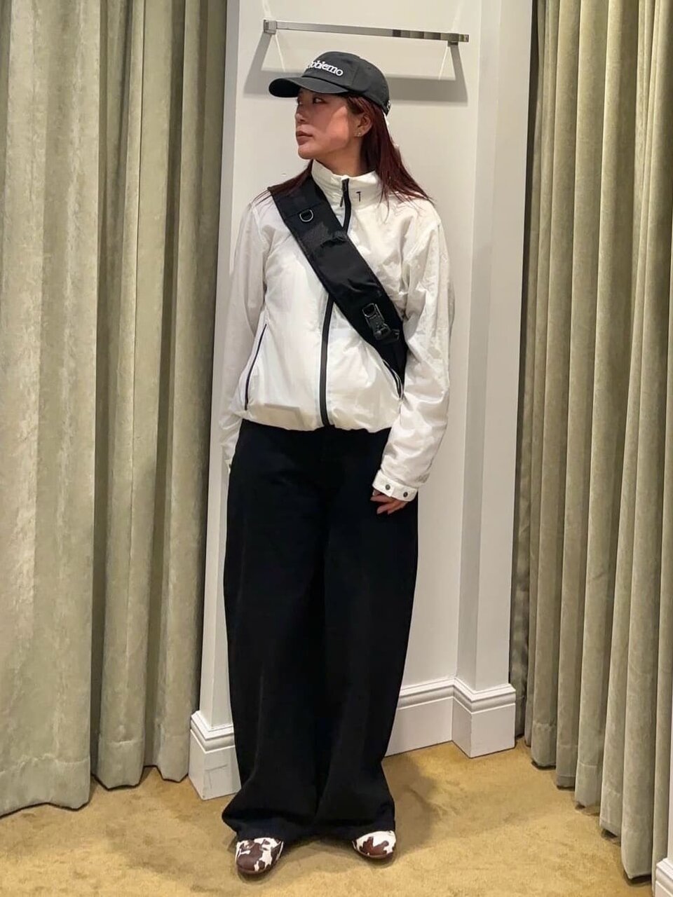白のシェルパーカーと黒のパンツを着た女性