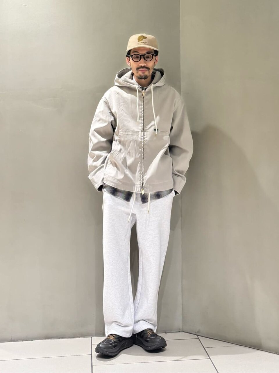 フーディージャケットを着てベージュのキャップを被った男性
