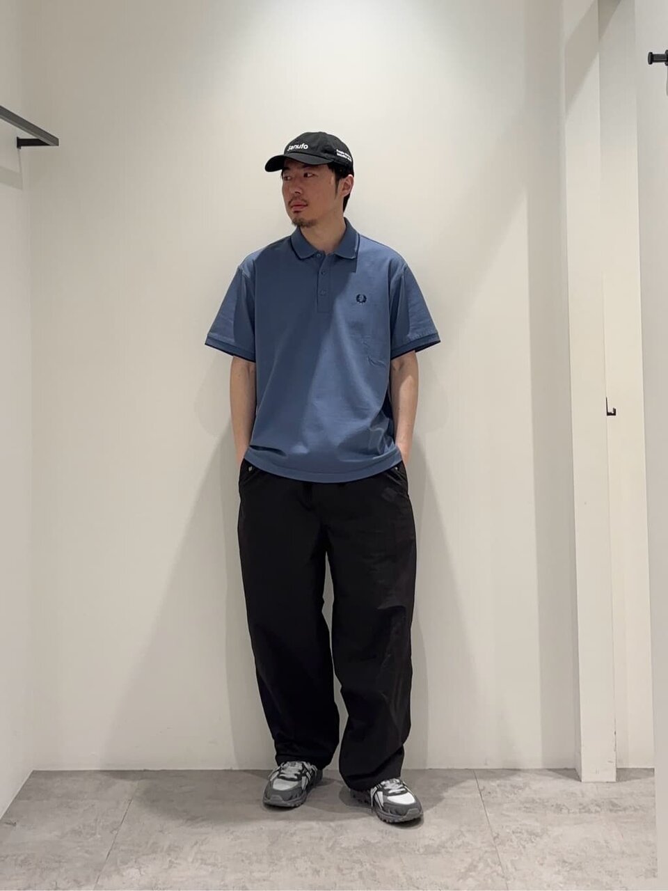 ブルーのポロシャツに黒のキャップを合わせた男性
