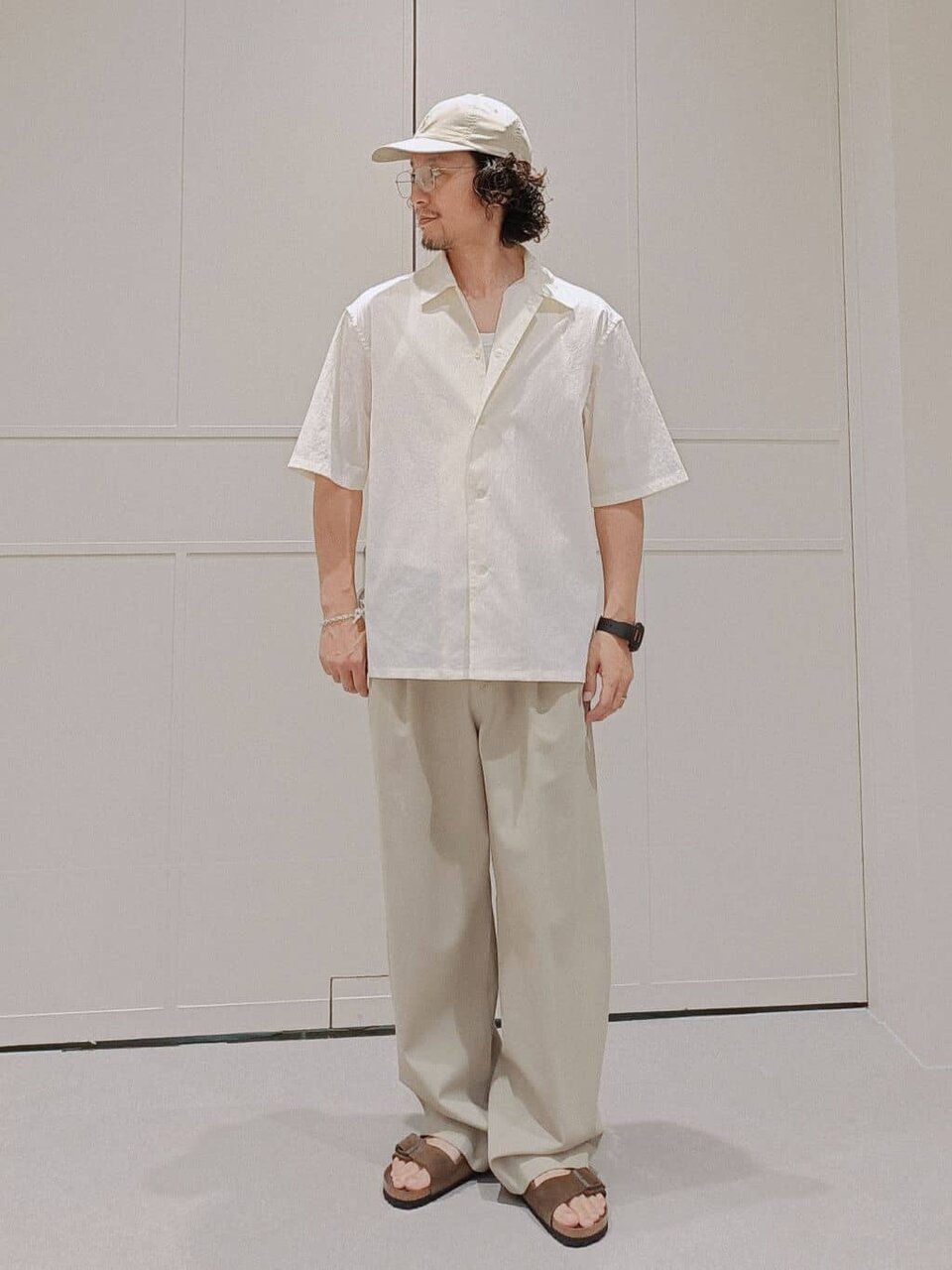 白のキャンプカラーシャツにベージュのキャップを合わせた男性