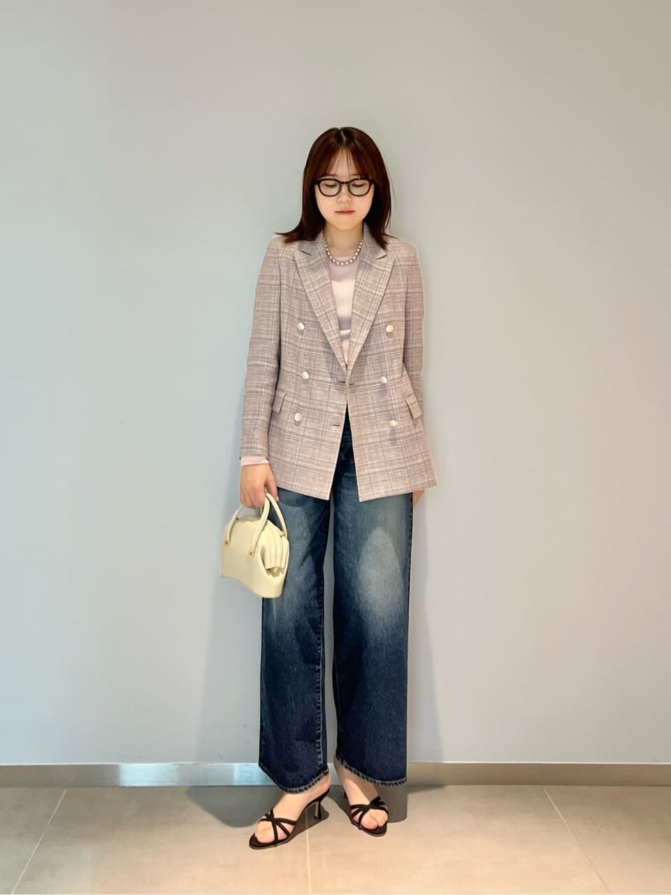 麻のジャケットとデニムパンツを着た女性
