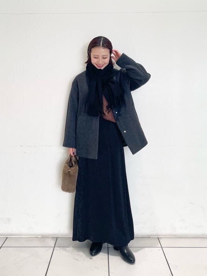 ノーカラーコートとマーメイドスカートを着た女性