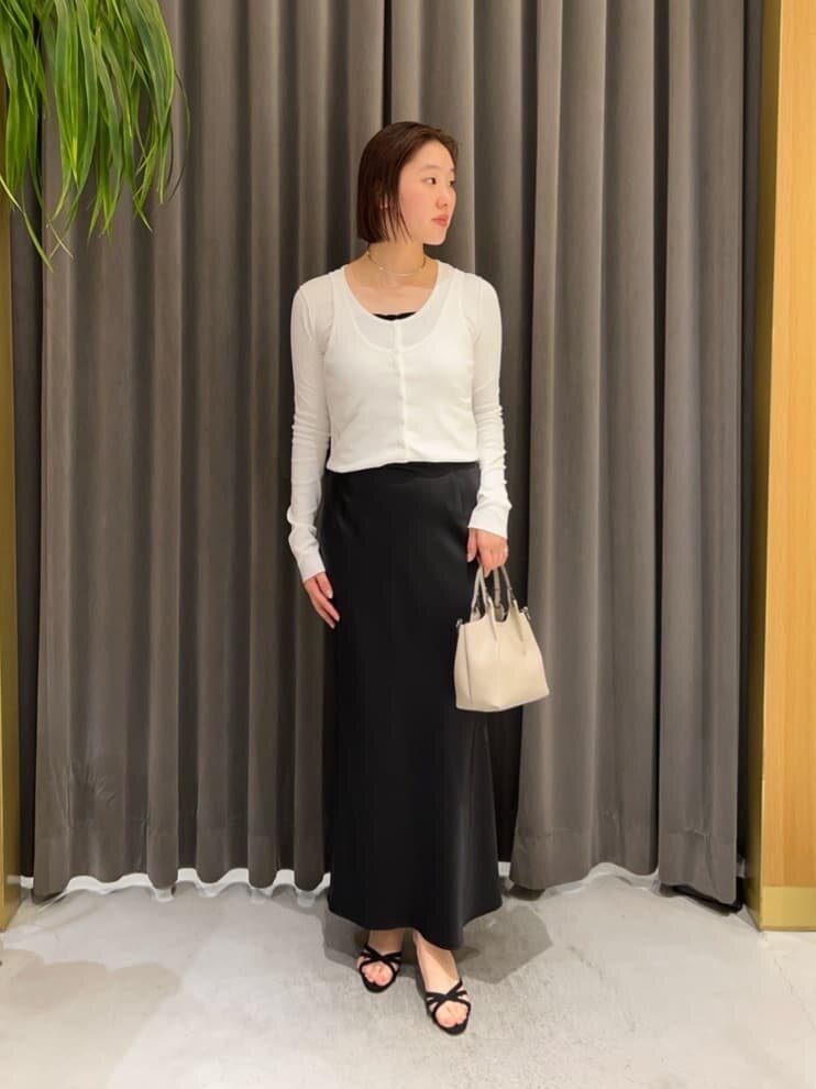 白のカーディガンとマーメイドスカートを着た女性