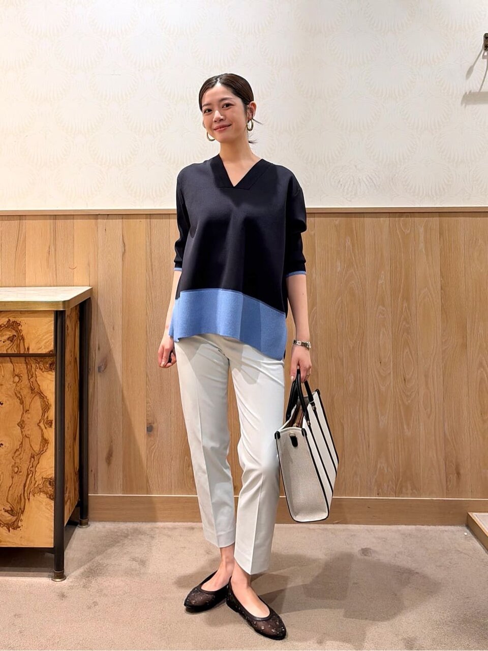 バイカラーニットとスラックスを着た女性