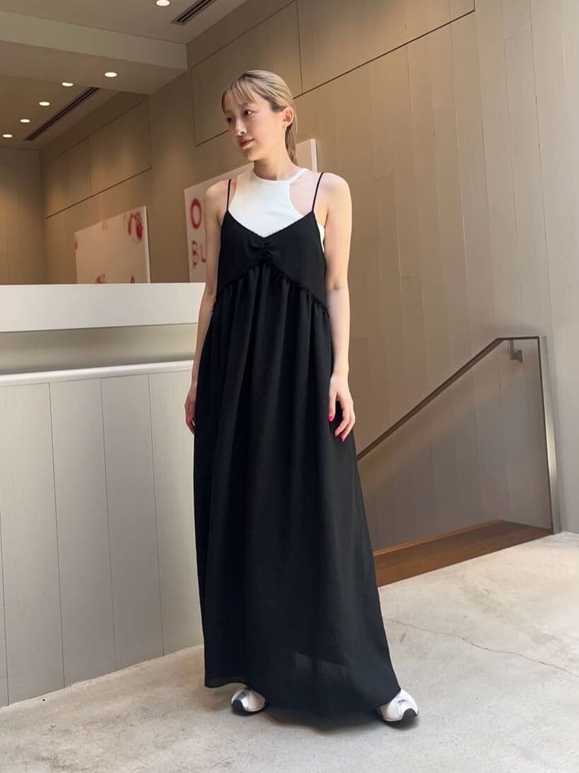 黒のキャミソールワンピースと白のタンクトップを着た女性