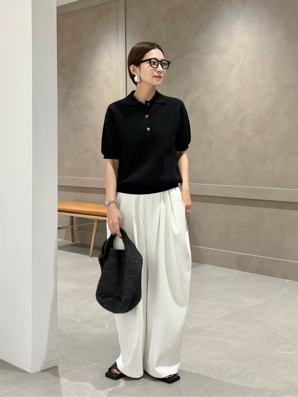 黒のポロニットと白のイージーパンツを着た女性