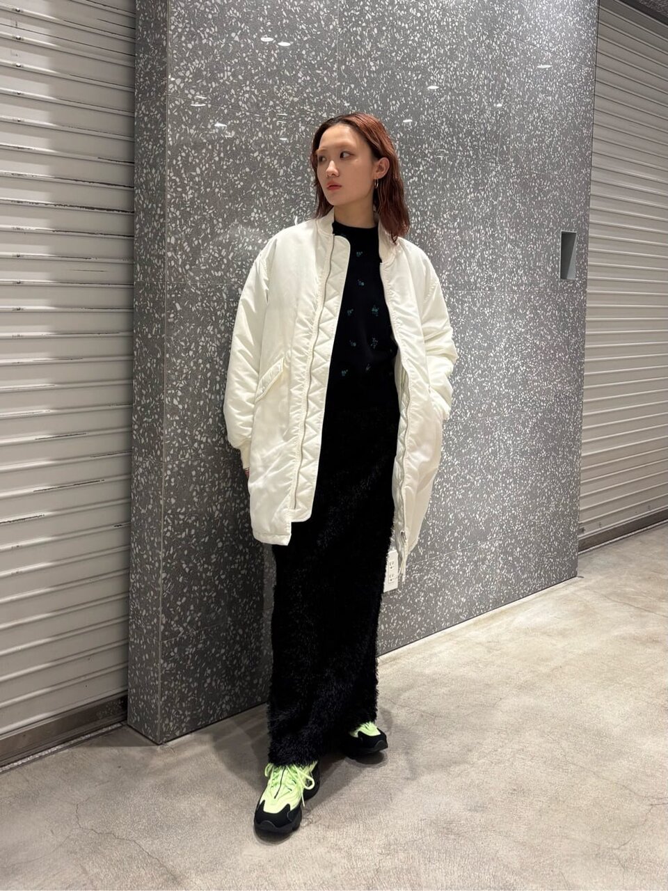 白のキルティングジャケットと黒のロングスカートを着た女性