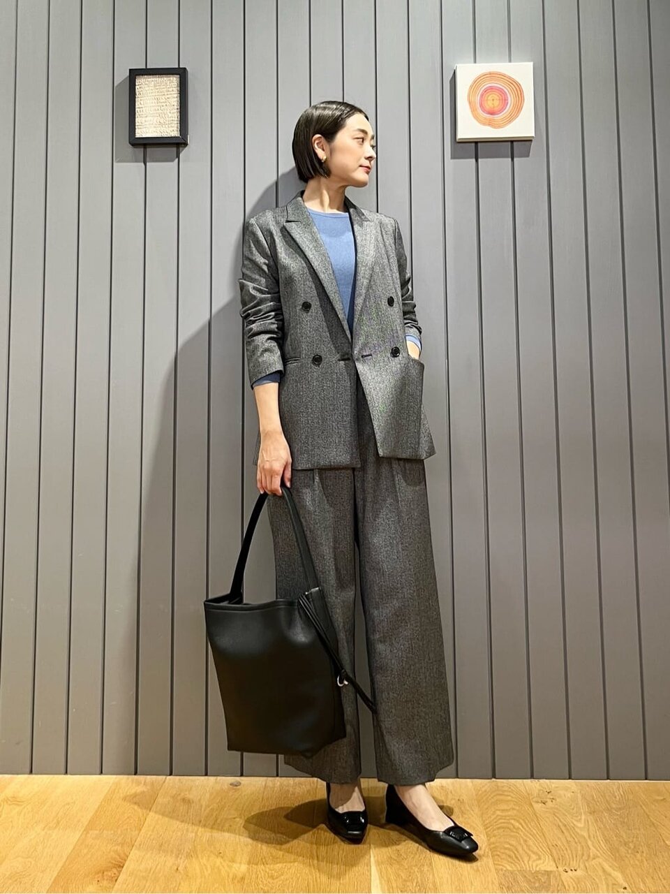 カーディガンとサックスブルーのプリーツスカートを着た女性