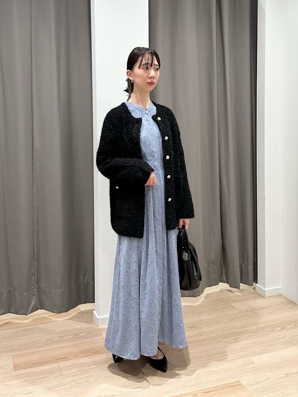 カーディガンとサックスブルーのプリーツスカートを着た女性