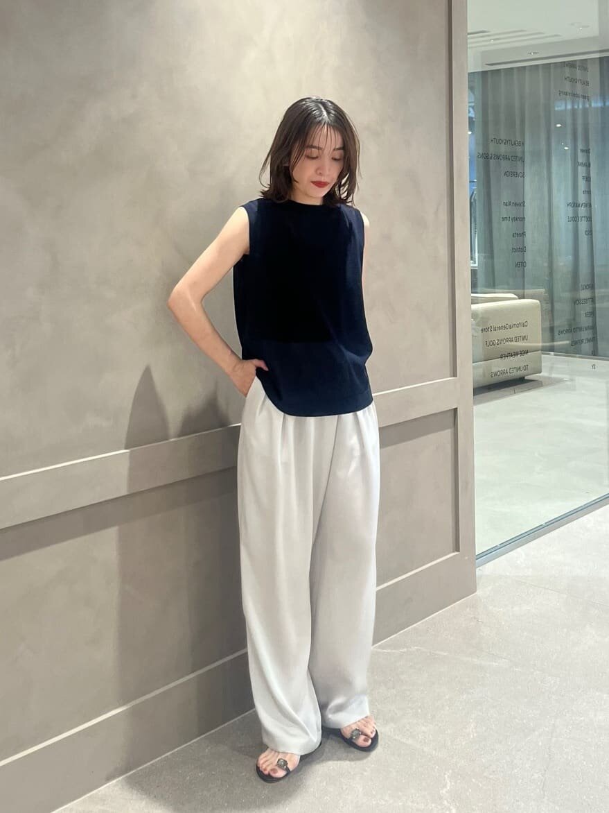 ノースリーブニットととサテンパンツを着た女性