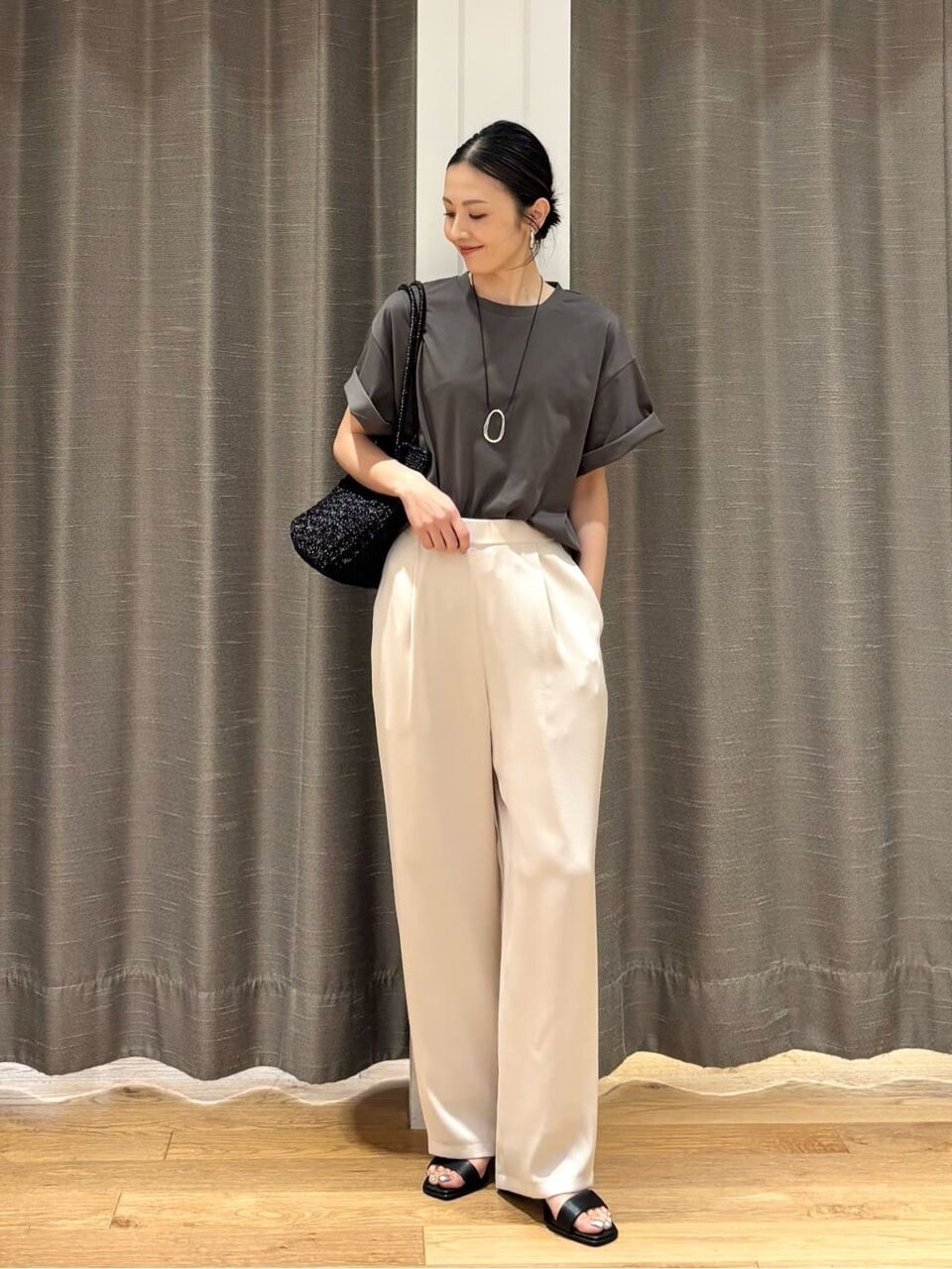 グレーのTシャツ白のサテンパンツを着た女性