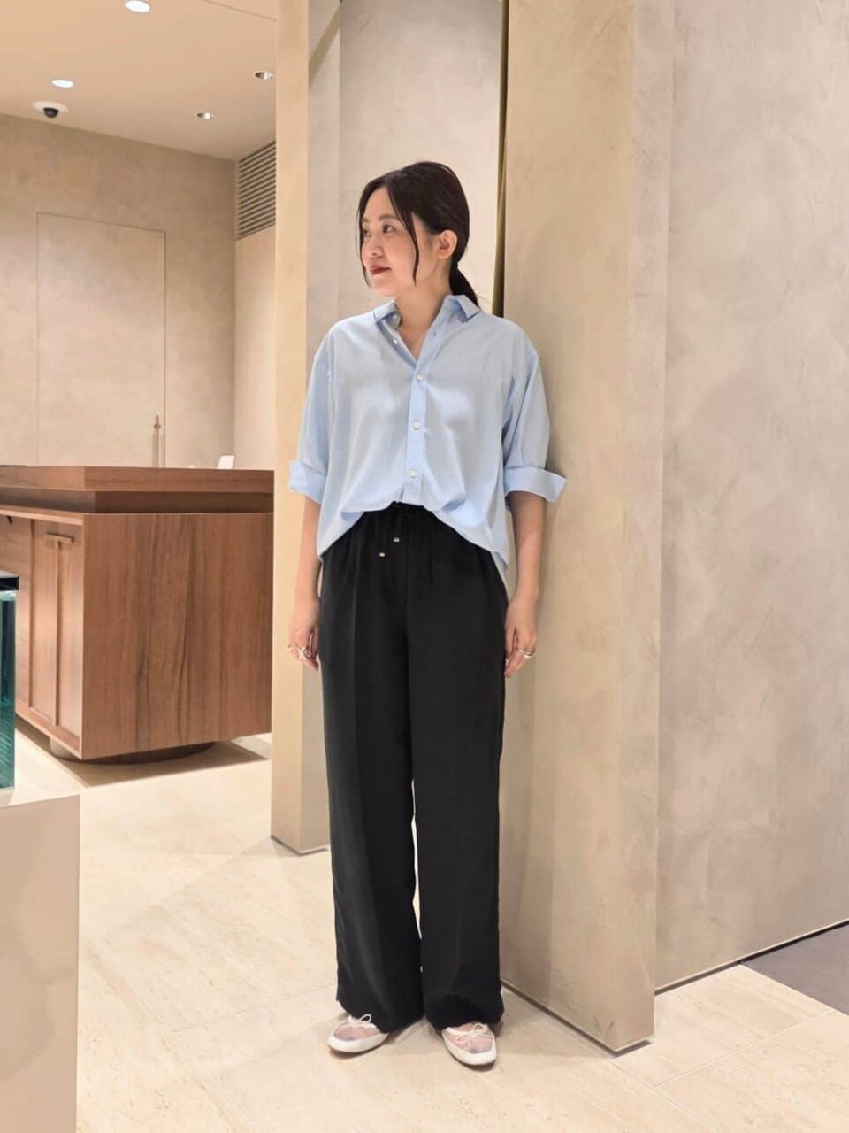 サックスブルーのシャツと黒のパンツを着た女性
