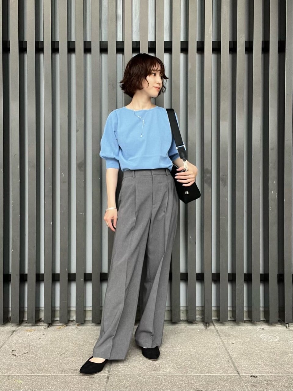 サックスブルーのニットとワイドパンツを着た女性
