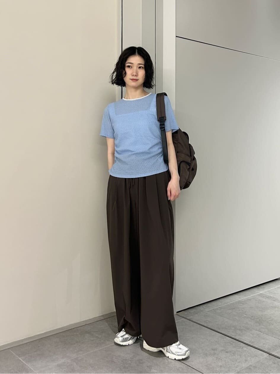 サックスブルーのカットソーとブラウンのパンツを着た女性