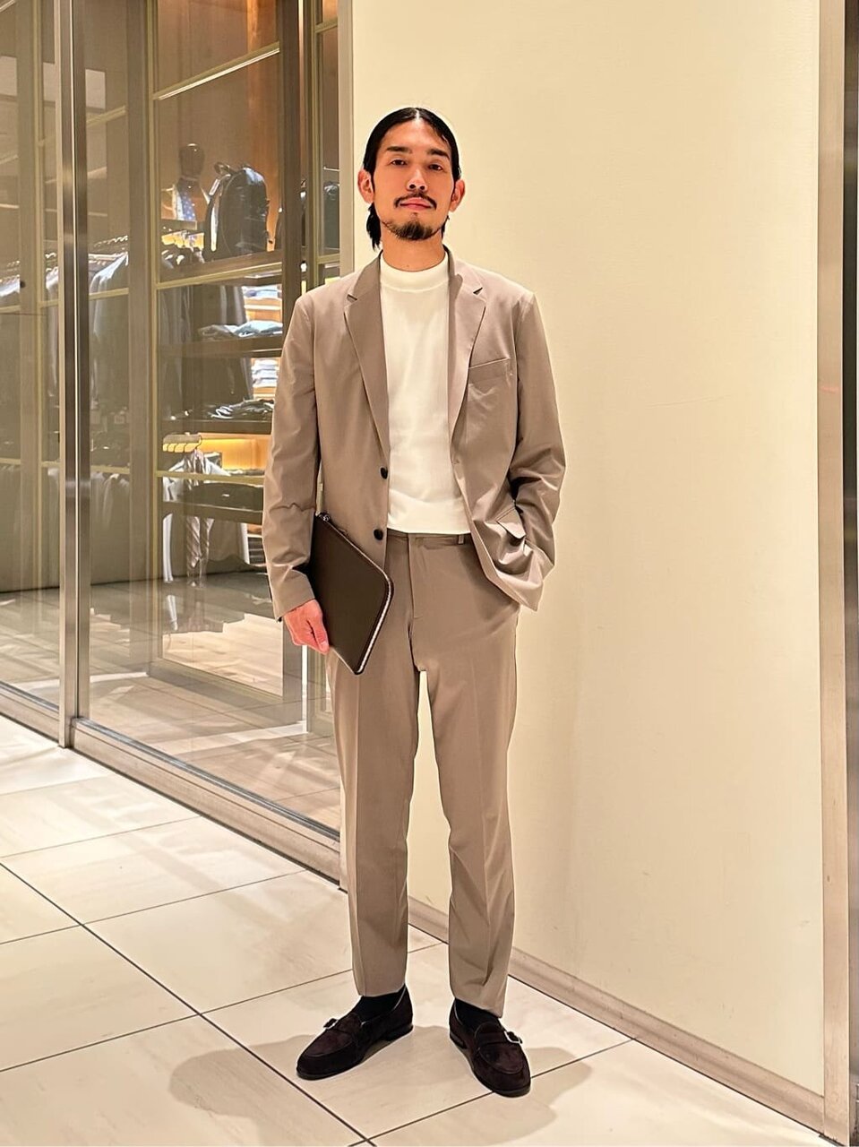 ベージュのジャケットとモックネックTシャツを着た男性