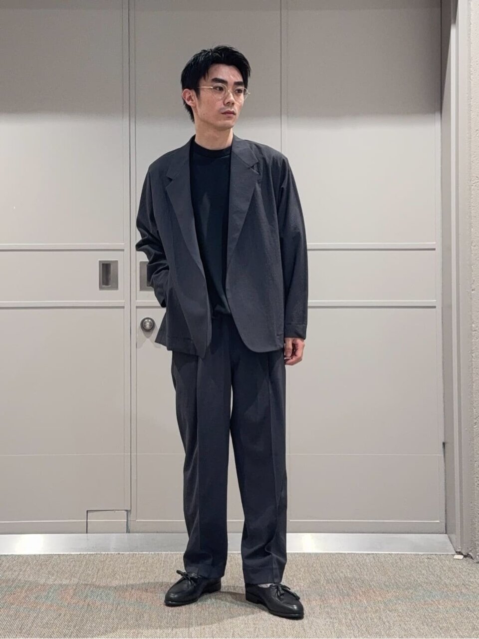 ダークグレーのジャケットと黒のTシャツを着た男性