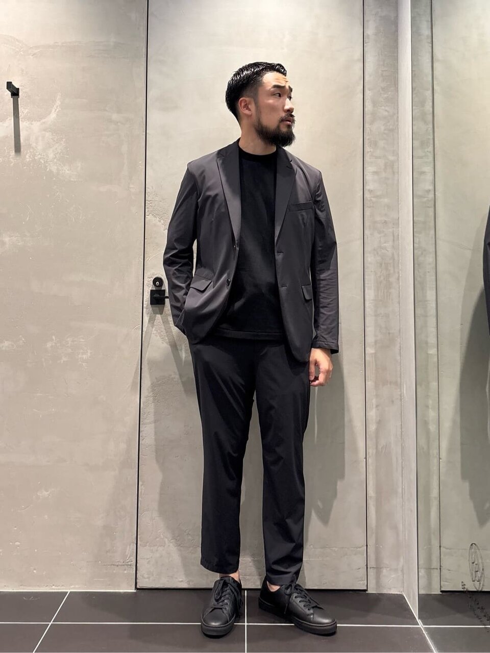 ダークグレーのジャケットと黒のTシャツを着た男性
