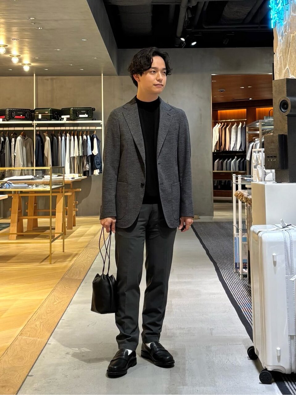 グレーのジャケットと黒のモックネックのTシャツを着た男性