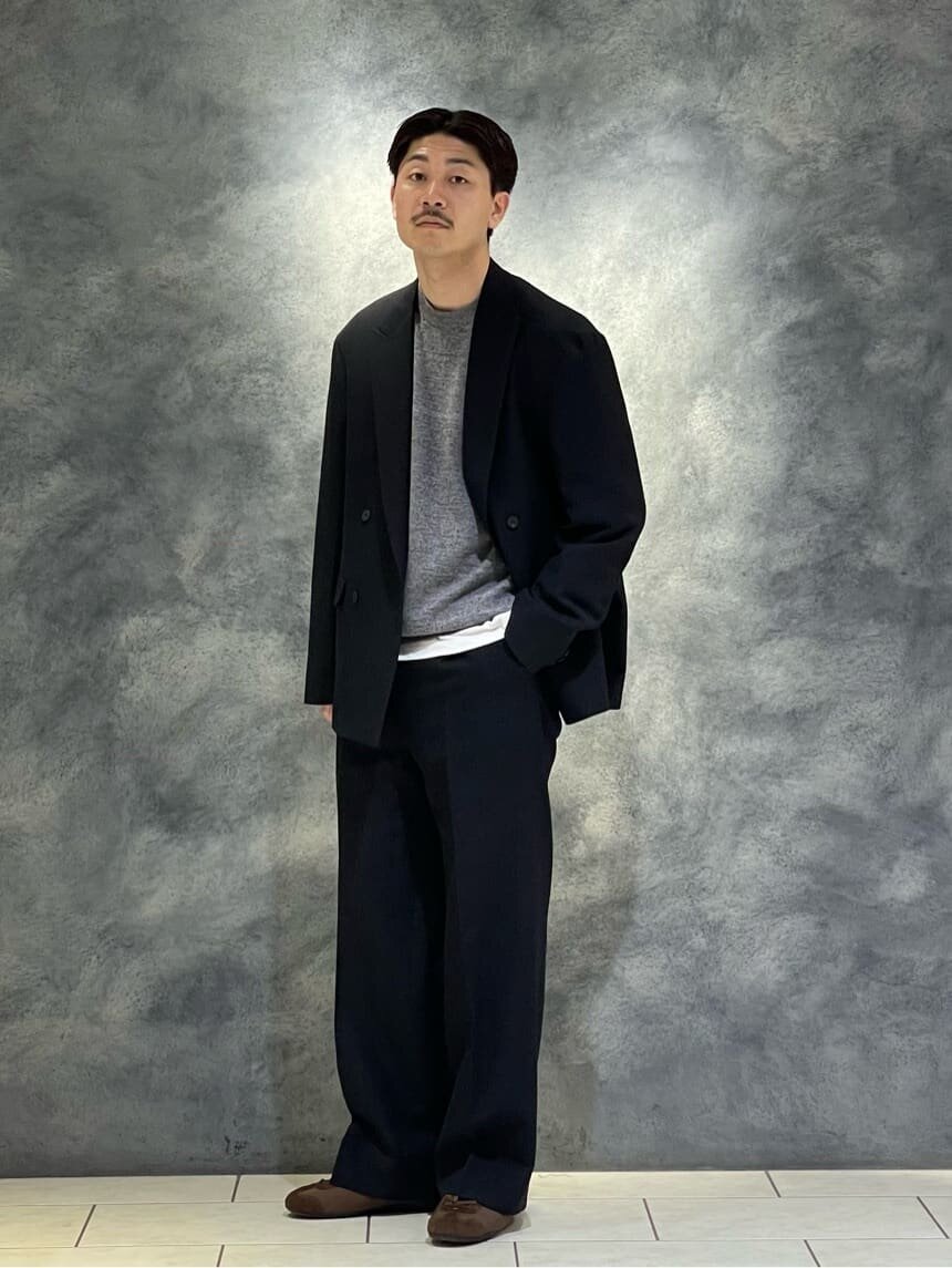 黒のセットアップとグレーのニットを着た男性